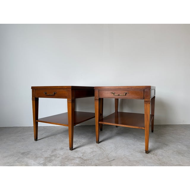 Beautiful pair of Hekman Neoclassical style wood end tables featuring a warm brown finish, brass-tone drawer pulls,...