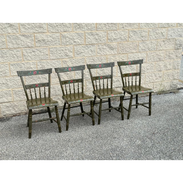 Charming set of four antique American painted wood side chairs featuring a rich ground with hand-painted floral decoration...