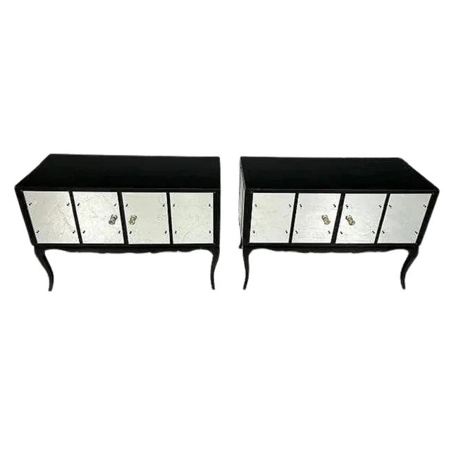 A pair of Hollywood Regency style cabinets featuring sleek black glass cases accented with mirrored door panels for a...