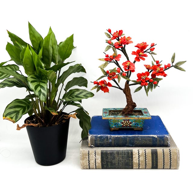 Charming vintage decorative flowering tree featuring carved red stone blossoms and green leaves arranged in a graceful,...