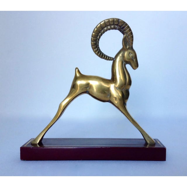 Vintage; Mid-century, solid brass ram bookend mounted on an oxblood red grained wood base, with inlaid brass perimeter...