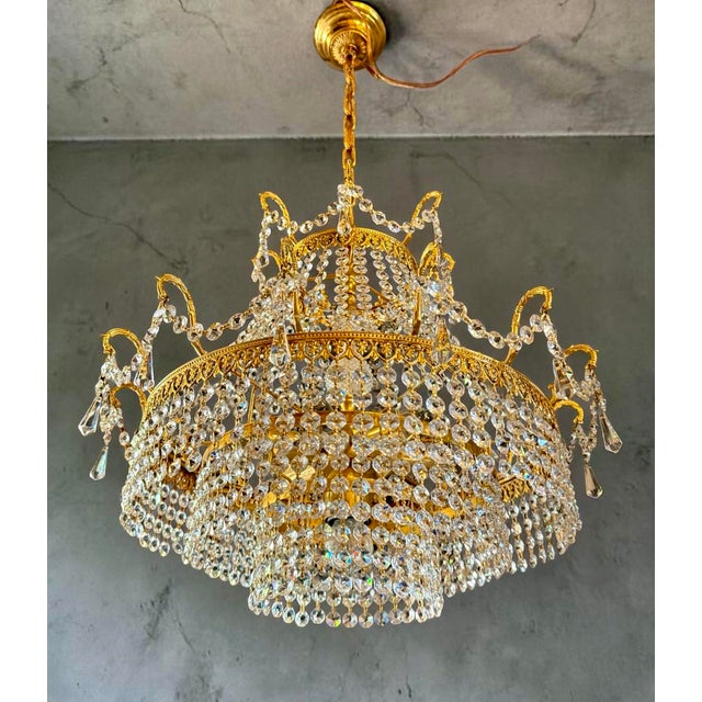 A true eye-catcher. This richly crafted antique chandelier exudes pure luxury and elegance. The gold-colored frame is...