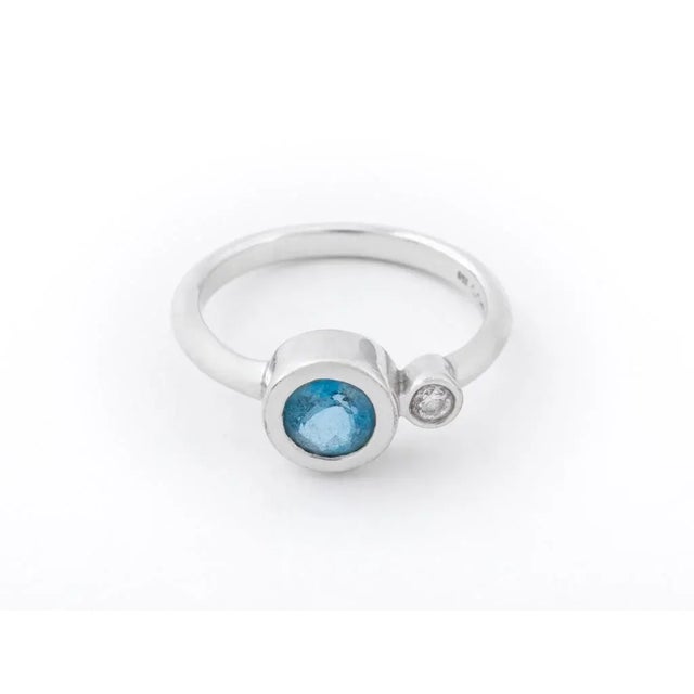 18K white gold ring, featuring one round aquamarine crystal weighing approx. 1.00 carat, adorned with a round diamond...