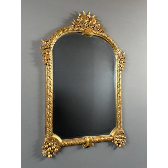A very elegant wall mirror in carved and gilded wood, dating from the 20th century. The frame, with its architectural...