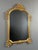 A very elegant wall mirror in carved and gilded wood, dating from the 20th century. The frame, with its architectural...