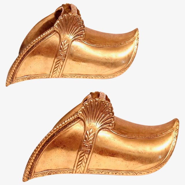 An elegant pair of heavy cast brass stirrups with Neoclassical relief decoration, the highlight being the bold anthemion...
