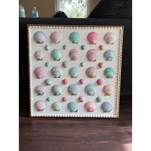A painted shell composition by Ohana Sea Designs, featuring real scallop shells individually painted in shades of pink,...