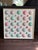 A painted shell composition by Ohana Sea Designs, featuring real scallop shells individually painted in shades of pink,...