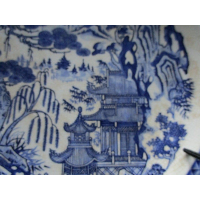 This is a rare blue and white porcelain charger/plate that is 12 inches in diameter. The backdrop is detailed with a...