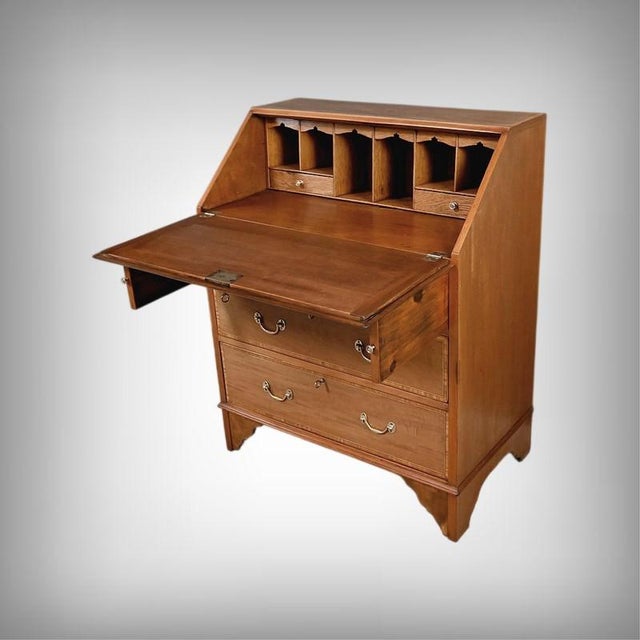 This English mahogany secretary desk is distinguished by its slanted drop-front, adorned with an oval marquetry medallion...