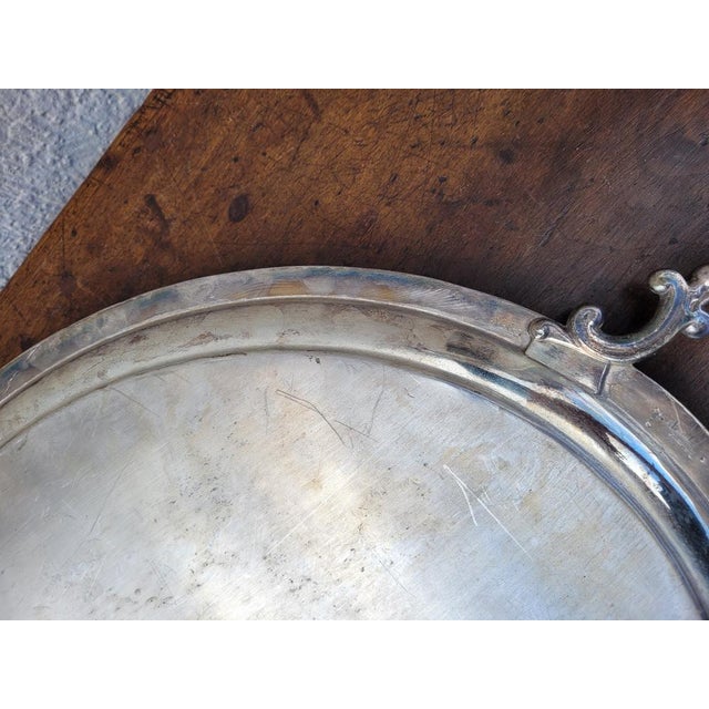 Oval-shaped silver metal tray, with handles with balls, decorated with leaves and garlands Traces of use, scratches and...