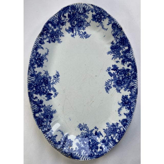 This beautiful platter has a subtle ruffed edge with a blue flow transfer-ware floral border. There is a stamped ID on the...