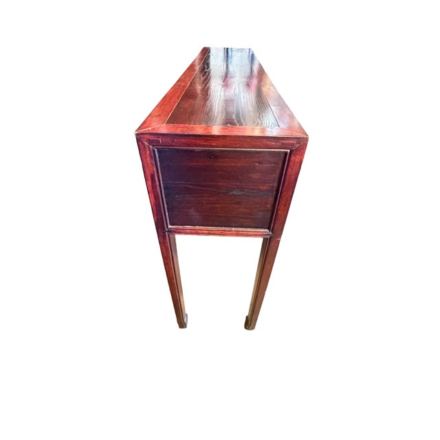 Asian-style wood console table (or writing desk) crafted with a warm reddish-brown finish, featuring five drawers arranged...
