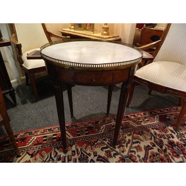 Louis XVI Style Mahogany and Marble Top Bouillotte Table, 19th Century. The circular white variegated marble top within a...