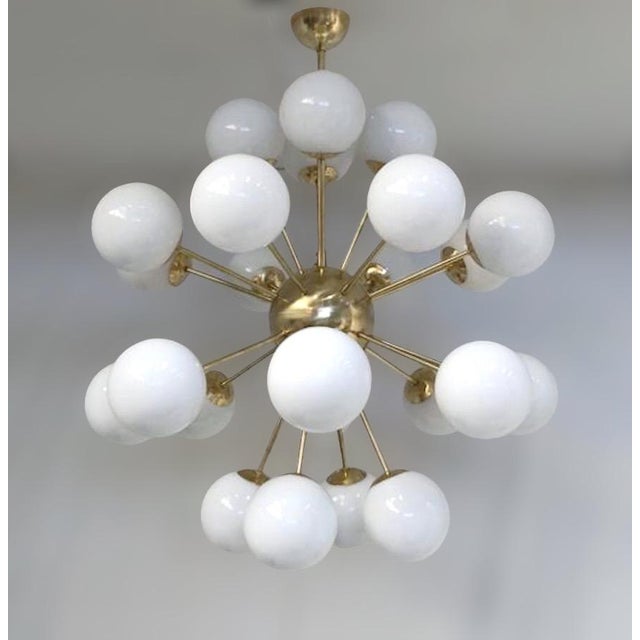 Italian sputnik chandelier with 24 glossy white Murano glass globes mounted on brass frame in unlacquered natural brass...