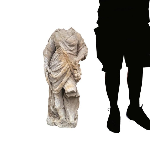 Soft stone sculpture depicting a standing, headless figure in a long, draped garment. Some chips, wear, and wear....