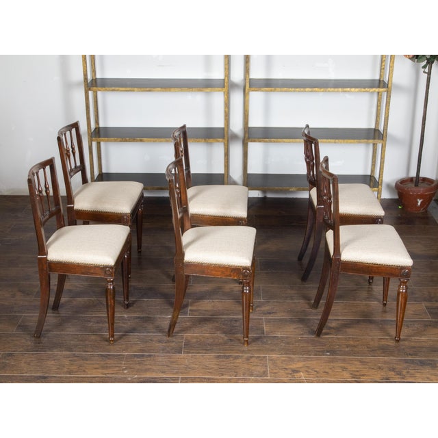A set of six Italian walnut dining room chairs from the early 19th century, with spindle-shaped backs, carved medallions...