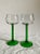 A pair of wine glasses in an elegantly simple design with green stem and clear glass bowl.