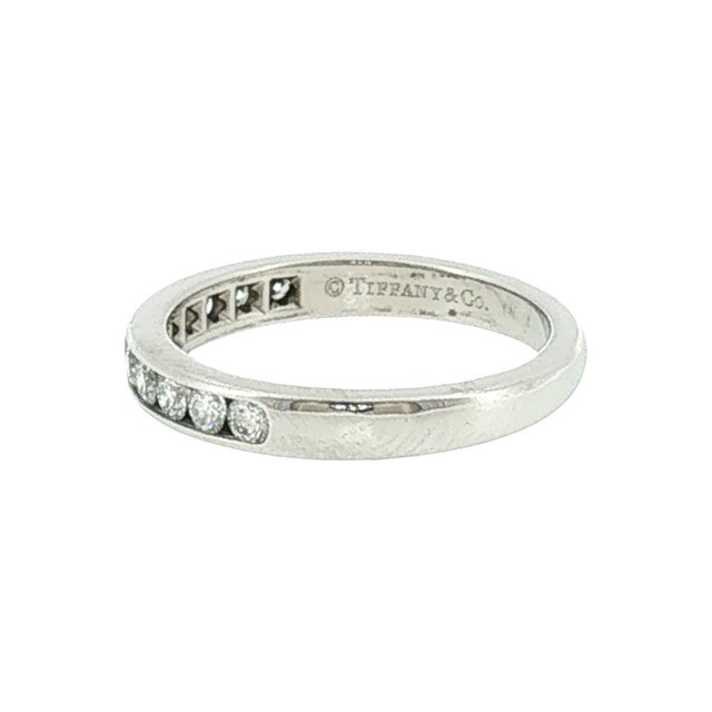 A late 20th-century Tiffany and Co. platinum wedding ring with brilliant-cut white diamonds. The 11 diamonds are channel...