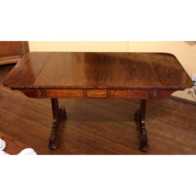 Circa 1820s sofa table in plum pudding mahogany with boxwood inlays and escutcheons. English, George IV. Opposing faux and...
