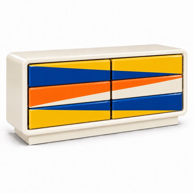 striking postmodern dresser featuring a glossy cream frame and bold, colorful drawer faces. Saturated blue, golden yellow,...