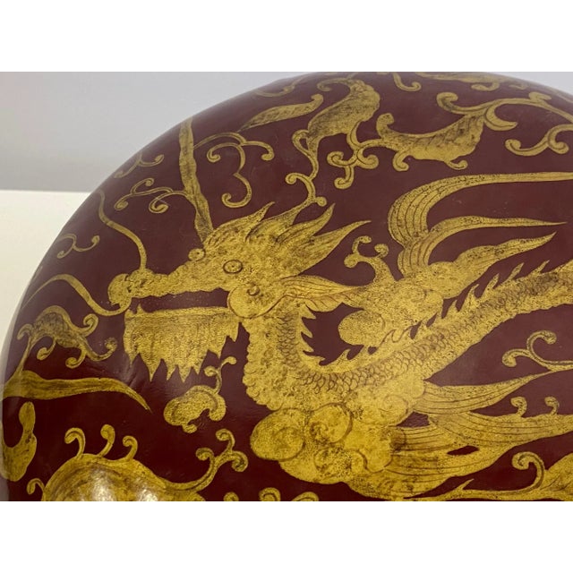Gorgeous round jewel of a red laquered lidded box having gold Asian inspired decoration with dragons and birds.