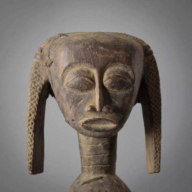 This finely carved female figure originates from the Baule people of CÃ´te d'Ivoire, a group renowned for their...