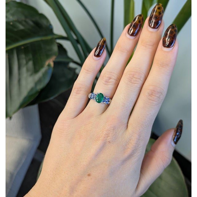 A 0.98ct zambian emerald oval ring set in solid 14K white gold, set with fifty earth mined diamonds and eight blue...
