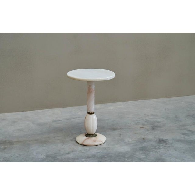 A beautiful side table in carved white and pink alabaster with elements in patinated brass. Italy, 1940s. This lovely side...