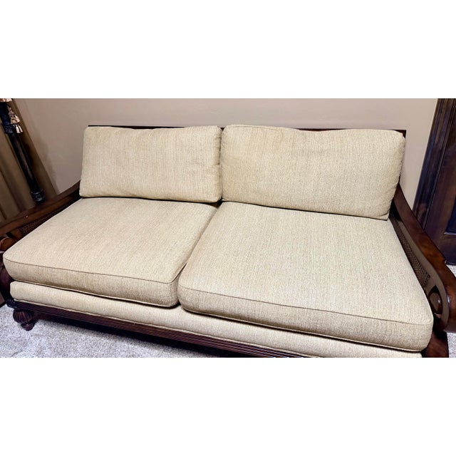 A distinctive “Susan” settee by Rachlin Classics, featuring an exposed carved-wood frame, elegant scroll arms, decorative...