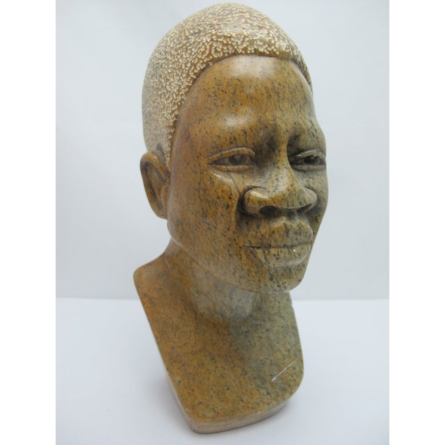 African hand carved bust made from a variegated stone showing detailed facial features and hair. Measures 9 1/2" tall x 3...