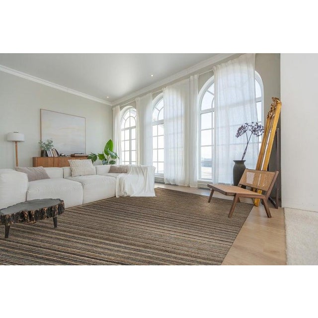 This brown earth tone area rug features a hand knotted pile weave and is constructed from durable polyester fibers....