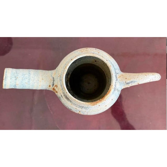 This whimsical ceramic pitcher blends functionality with sculptural flair, its exaggerated spout and handle giving it a...