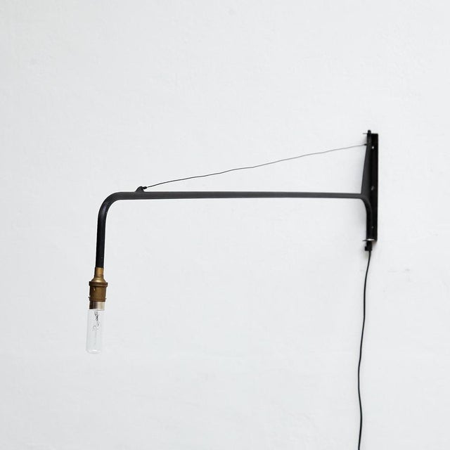 This wall lamp, inspired by the iconic designs of Jean Prouvé, was manufactured in France around 1970. with its sleek and...