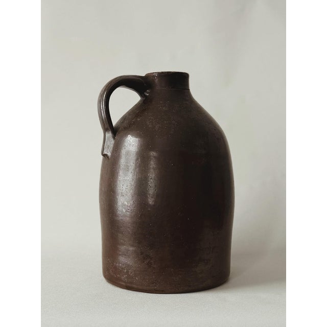 Hand-thrown stoneware jug in warm chocolate brown with natural glaze finish. Classic utilitarian form; functional handle;...