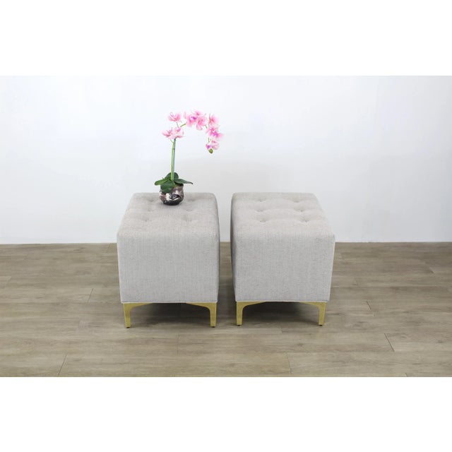 Elegant pair of custom design ottomans upholstered in a soft cream chenille textile and supported by elegant Italian style...