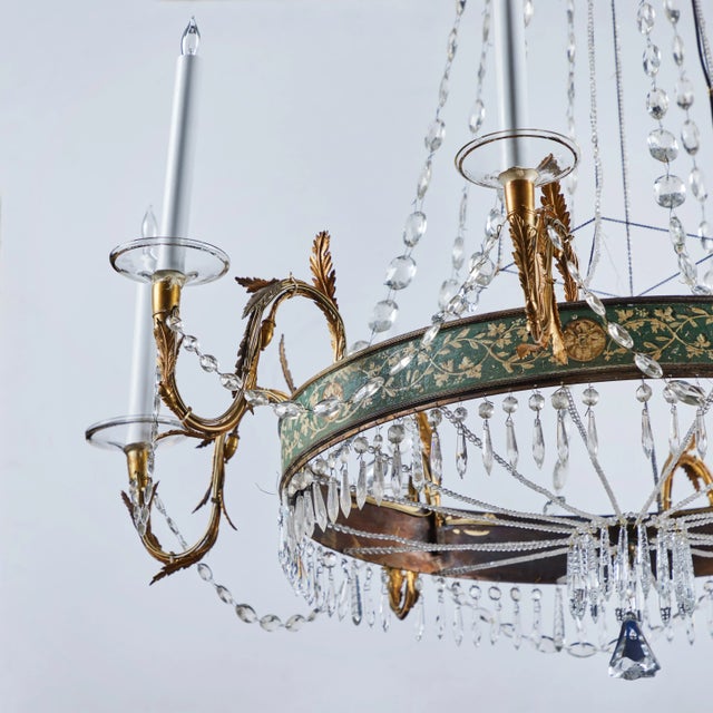 A beautiful crystal chandelier with hand painted bronze ring with foliate and flora designs supporting the elegant 8...