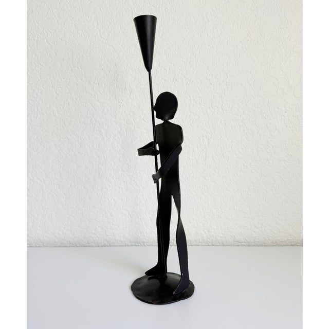 Vintage mid-20th-century folk art style taper candle holder featuring a stylized male form. Finished in satin black paint...