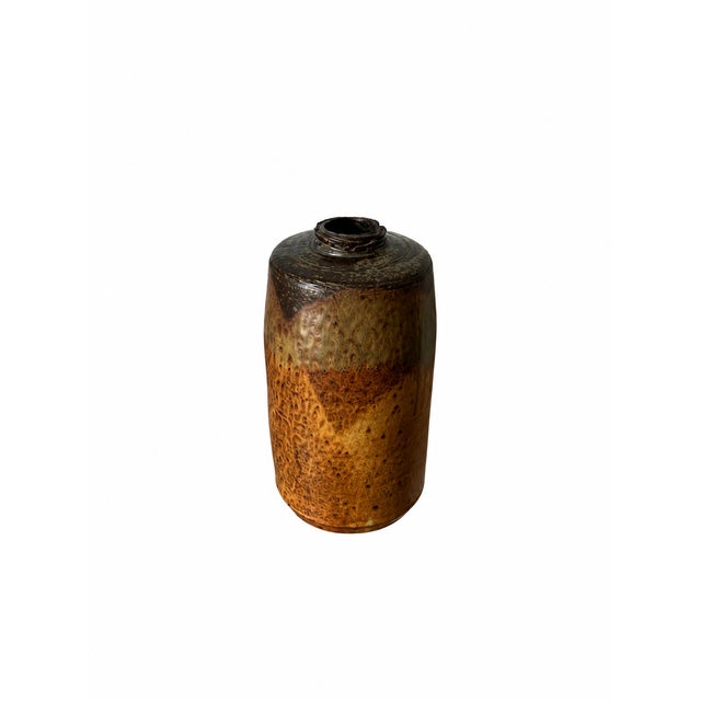 A substantial decorative vessel featuring a cylindrical body, rounded shoulders and a narrow opening. Rich amber, ochre...