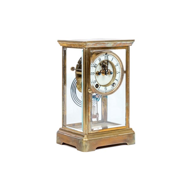 An antique brass four-glass crystal regulator mantel clock by the New Haven Clock Co. with a beveled glass case, white...