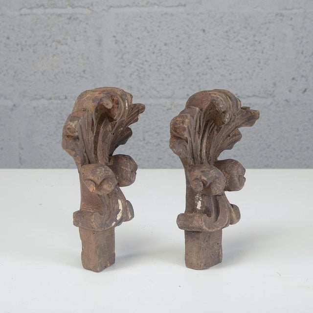 A refined pair of vintage hand-carved wooden ornaments, a testament to fine antique cabinetmaking. The pieces feature a...