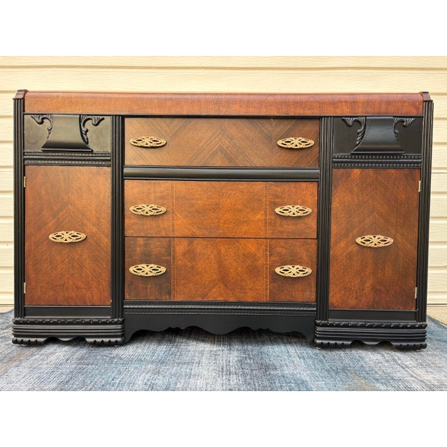 Vintage Art Deco waterfall sideboard or buffet featuring burl wood veneers, black-painted accents, and ornate brass...