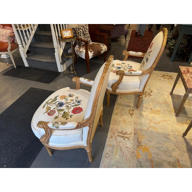 This is a pair of antique French gilded wood chairs. The wood is beautifully carved with intricate details. The legs are a...