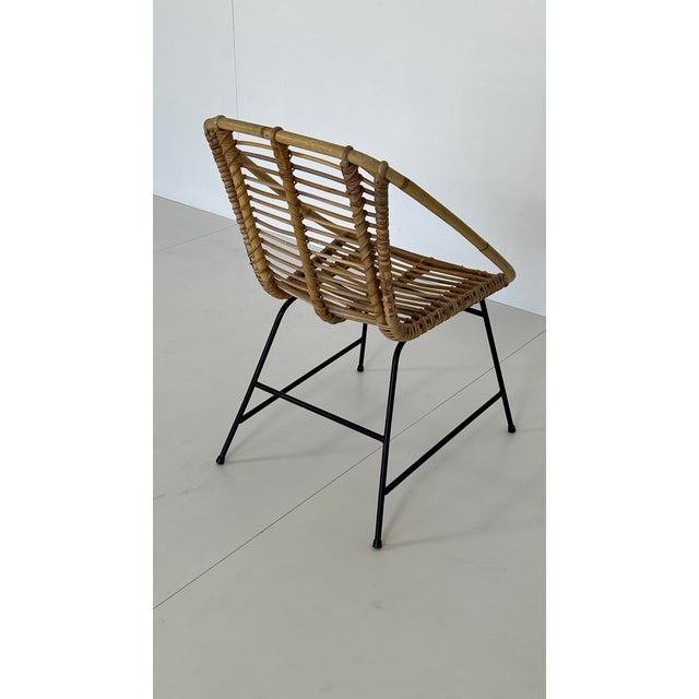 Woven rattan lounge chair, Italian design. Fits perfectly into a minimalist 1960s lounge setting. Matte black metal base.