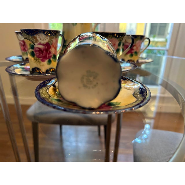This set displays intricate floral designs, particularly the roses, rich cobalt blue, and gilt accents typical of Nippon...
