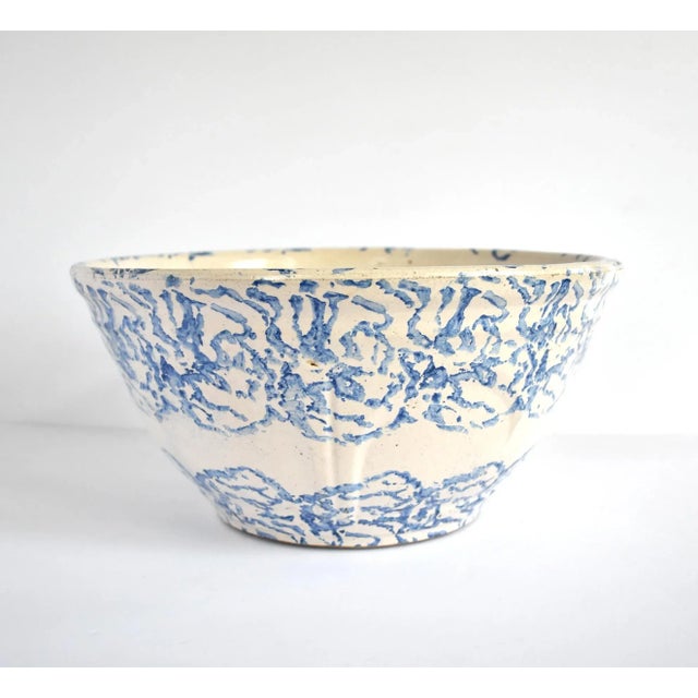 An antique, 19th-century, c. 1880-1890 mixing bowl in heavy stoneware mold-pressed pottery with a cream base and blue...
