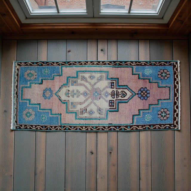 This exquisite vintage Oushak mat features a soft, sun-faded palette of pastel pink and sky blue that brings a serene,...