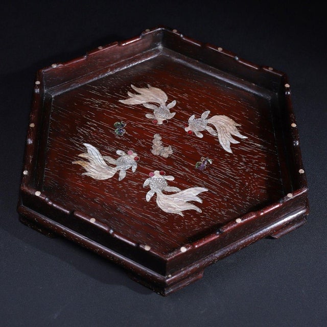 This is a striking, hexagonal wooden tray featuring intricate mother-of-pearl (nacre) inlay. Crafted from a dark, richly...