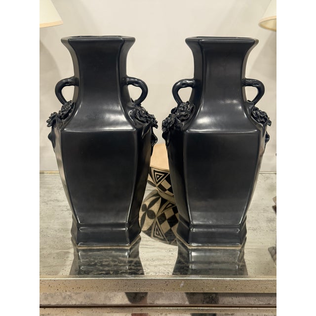 Pair of black-dark grey Chinese vases. Jug style handles with a floral motif. No chips or cracks. There is a seal on the...