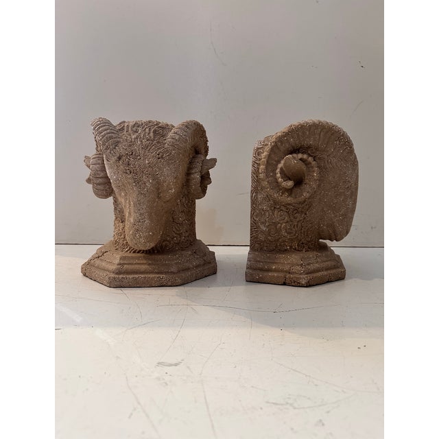 A pair of ram head bookends crafted in faux stone composite, featuring intricate horn and fleece detailing that gives them...